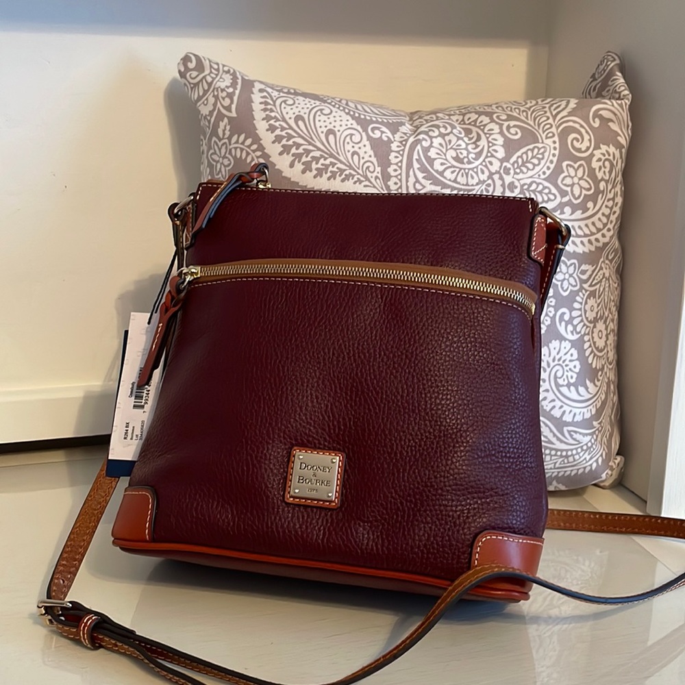 Brand new wine colored Dooney and Bourke leather crossbody bag. Adjustable strap